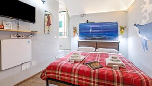 Ein Hotelzimmer mit einem Bett, einem Flachbildfernseher, einem Gemälde mit einem Segelboot und einer Wandkarte.