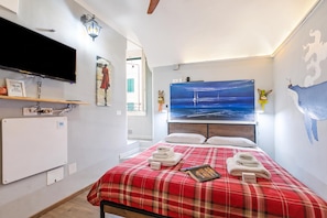 A hotel room with a bed, a flat-screen TV, a painting of a sailboat, and a wall map. - Domus Piazza Brigida Near Beach & Casino (Sanremo)
