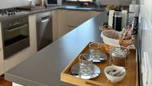 Une cuisine moderne dotée d’un long plan de travail, d’appareils électroménagers en acier inoxydable et d’une fenêtre laissant entrer la lumière naturelle.