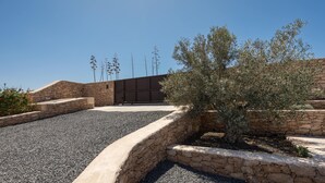 Un bâtiment moderne avec une façade en pierre, une allée gravillonnée et un petit arbre.