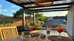 Une table en bois avec deux boissons, un bocal de noix et un set de table en fibres tressées.