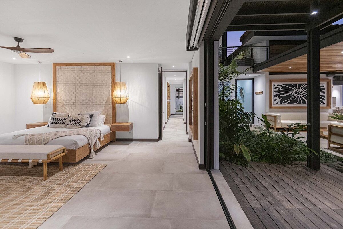 A modern bedroom with a bed, bedside tables, and a view of the outdoor area.