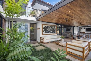 A modern outdoor living area with a wooden ceiling, a large abstract wall art piece, and a seating arrangement.