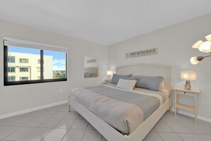 A bedroom with a bed, bedside tables, a window, and a sign on the wall. - Beachfront 3B/2B Sandarac Vacation Condo 702A. Direct gulf view! (Fort Myers Beach)