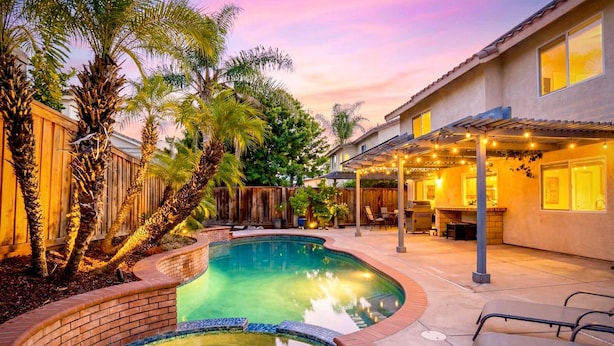 A backyard with a swimming pool, patio furniture, and a covered outdoor area with string lights. - Luxury Wine Country Home With Pool Spa (Murrieta)