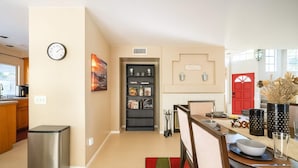 A modern kitchen with a built-in stove, a small trash bin, and a dining area with a table set for two. - Luxury Wine Country Home With Pool Spa (Murrieta)