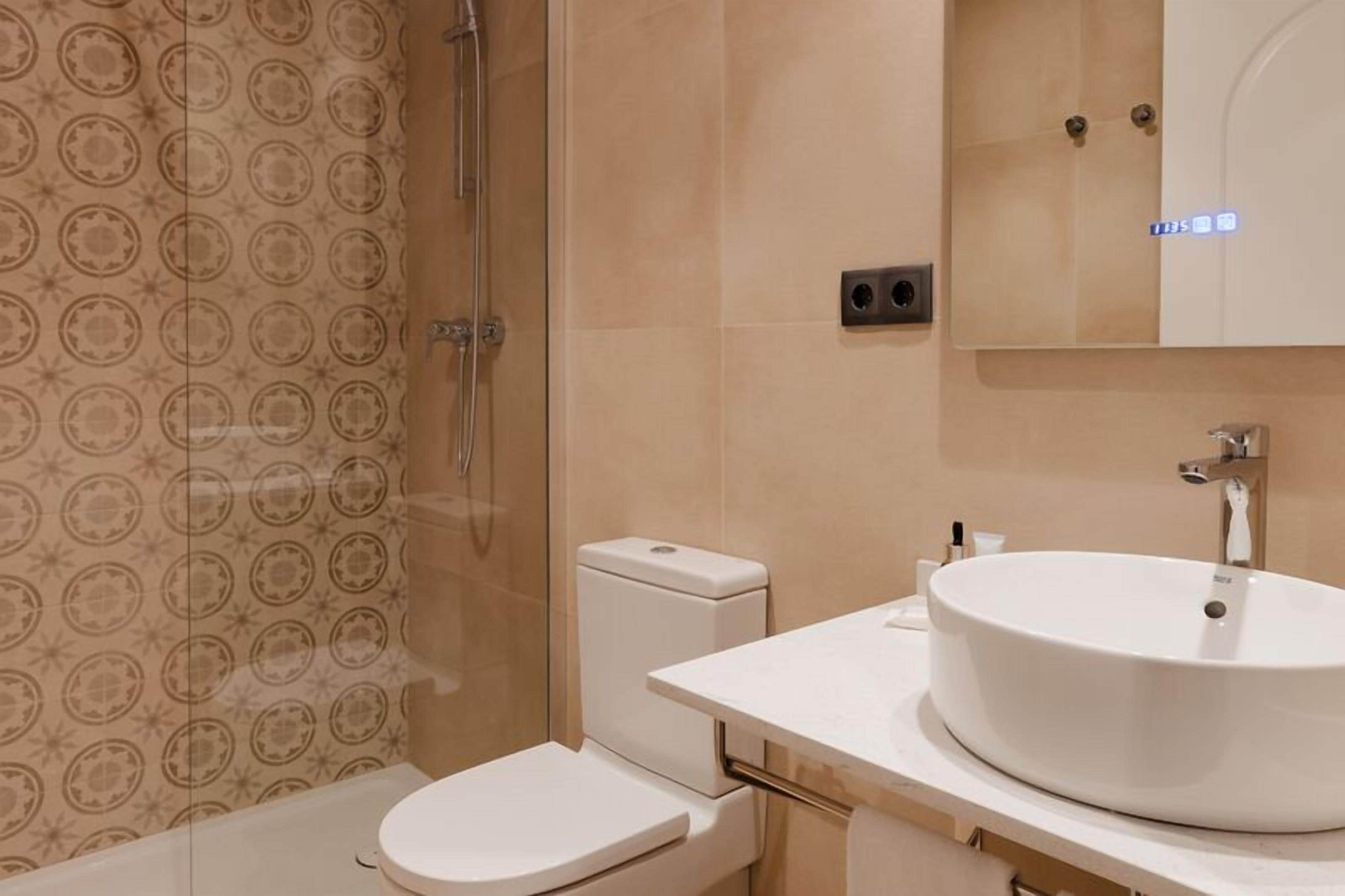 Een moderne badkamer met douche, toilet en wastafel.