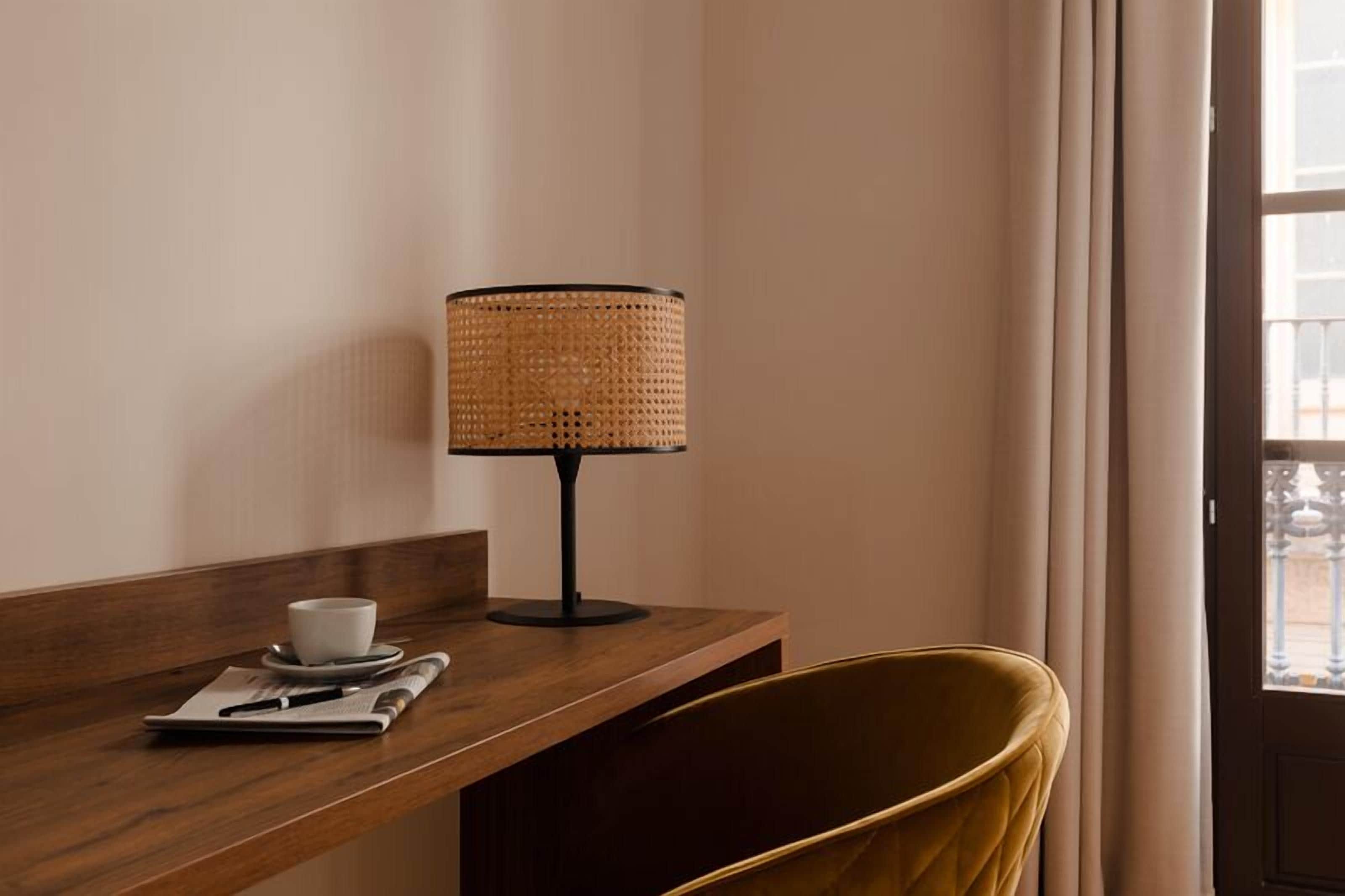 A wooden desk with a woven lamp, a cup, and a notepad.