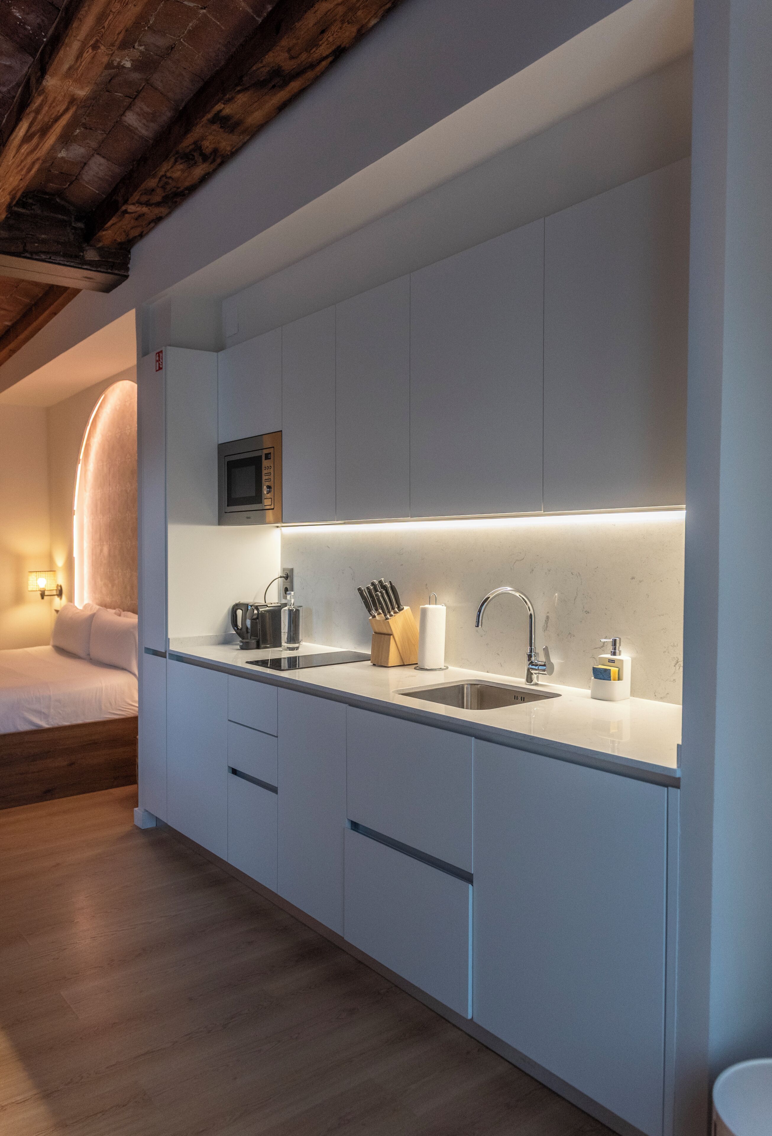 A modern kitchen with a built-in microwave, a sink, and a countertop with utensils.