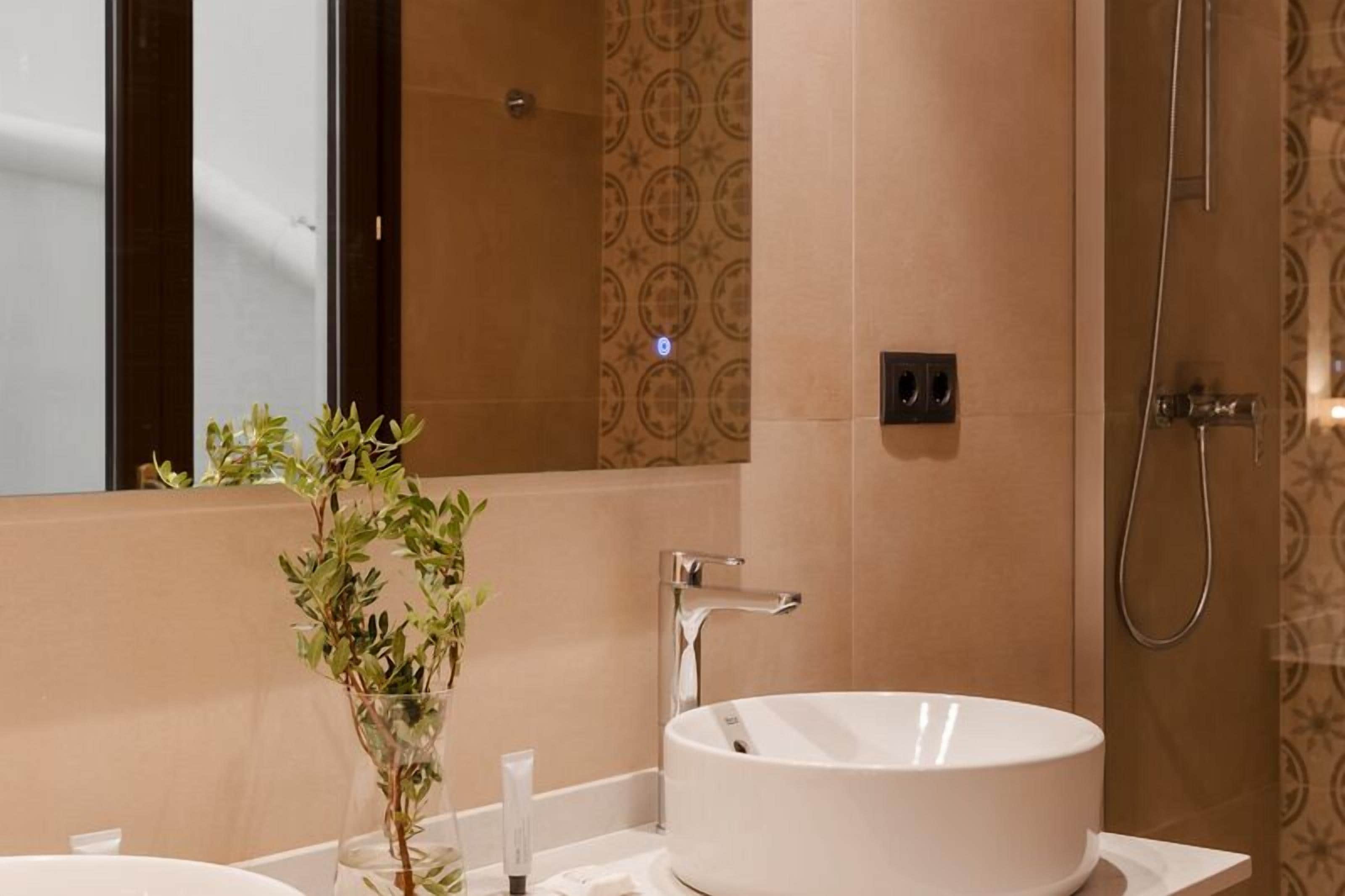 Un baño con un lavabo blanco, un espejo y una ducha.