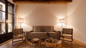 Ein gemütliches Wohnzimmer mit einer Couch, zwei Sesseln, einem Couchtisch und zwei Stehlampen.