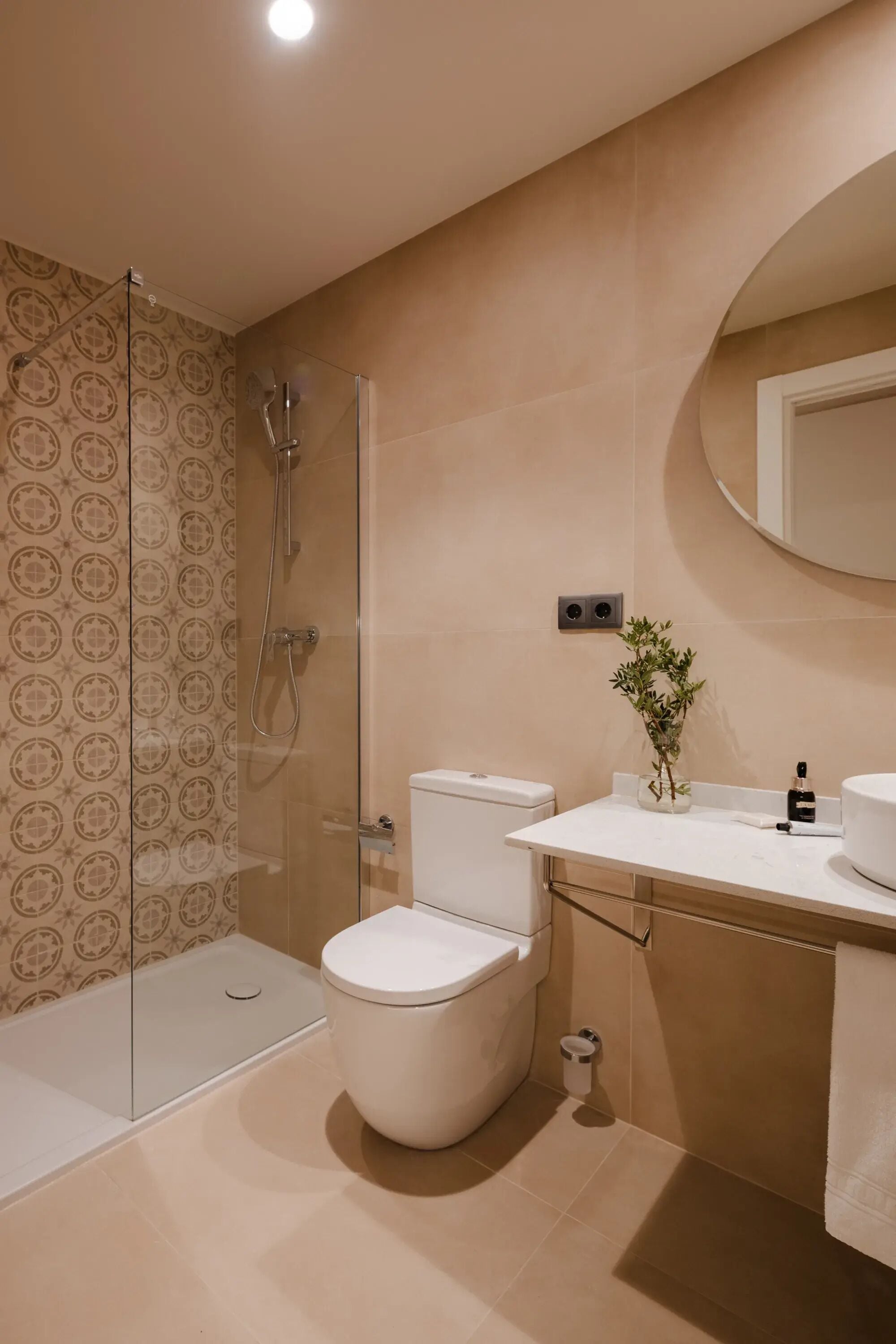 A modern bathroom with a glass shower enclosure, a toilet, and a sink with a mirror above.