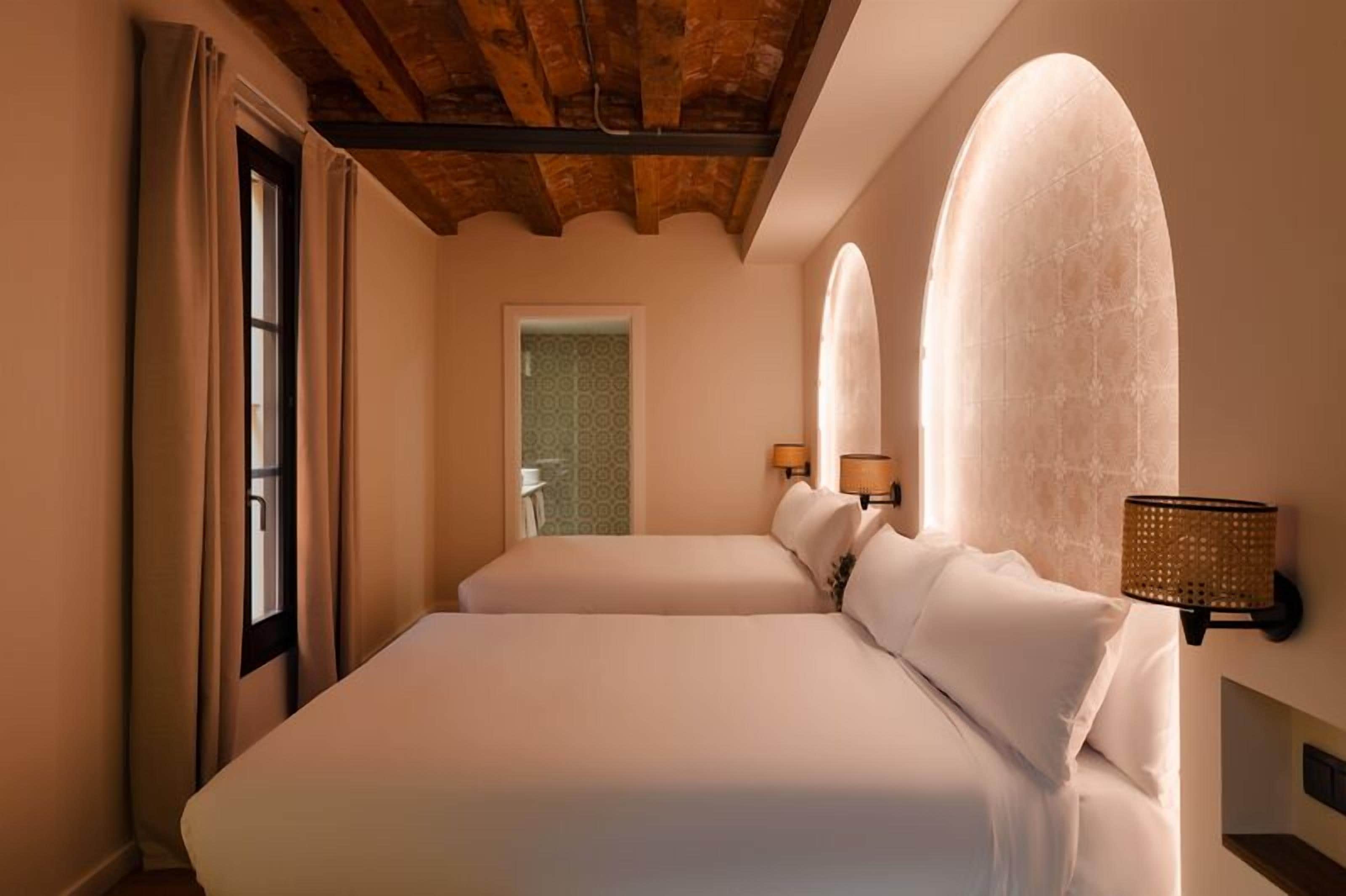 A hotel room with a large bed, two bedside lamps, and a wooden ceiling.