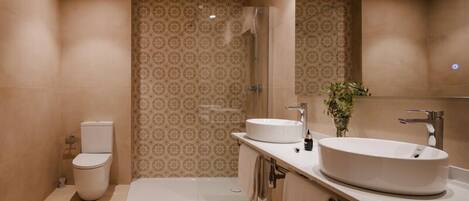 A modern bathroom with a toilet, a shower, and a vanity with a large sink.