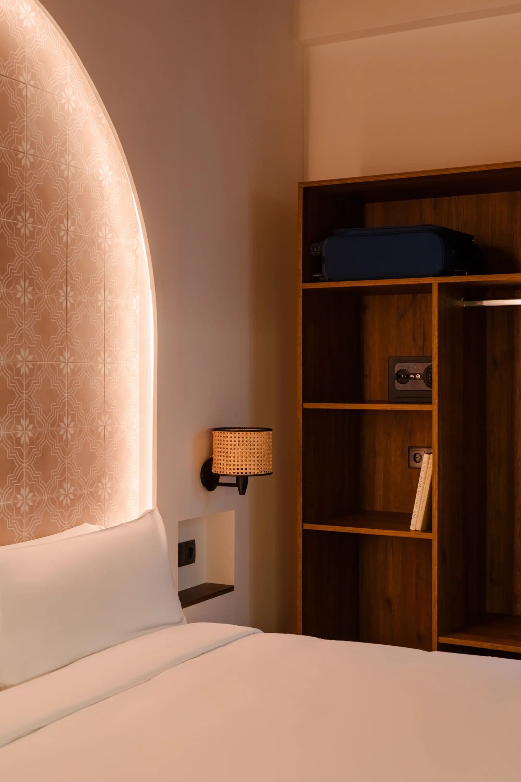 Ett hotellrum med en stor säng, en garderob i trä och en vägglampa.