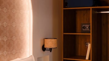 Ett hotellrum med en stor säng, en garderob i trä och en vägglampa.