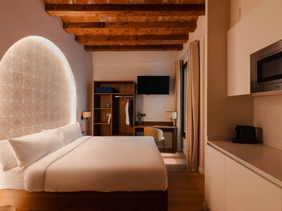 Ein Schlafzimmer mit einem großen Bett, Holzbalkendecke, Fernseher und einer Minibar.