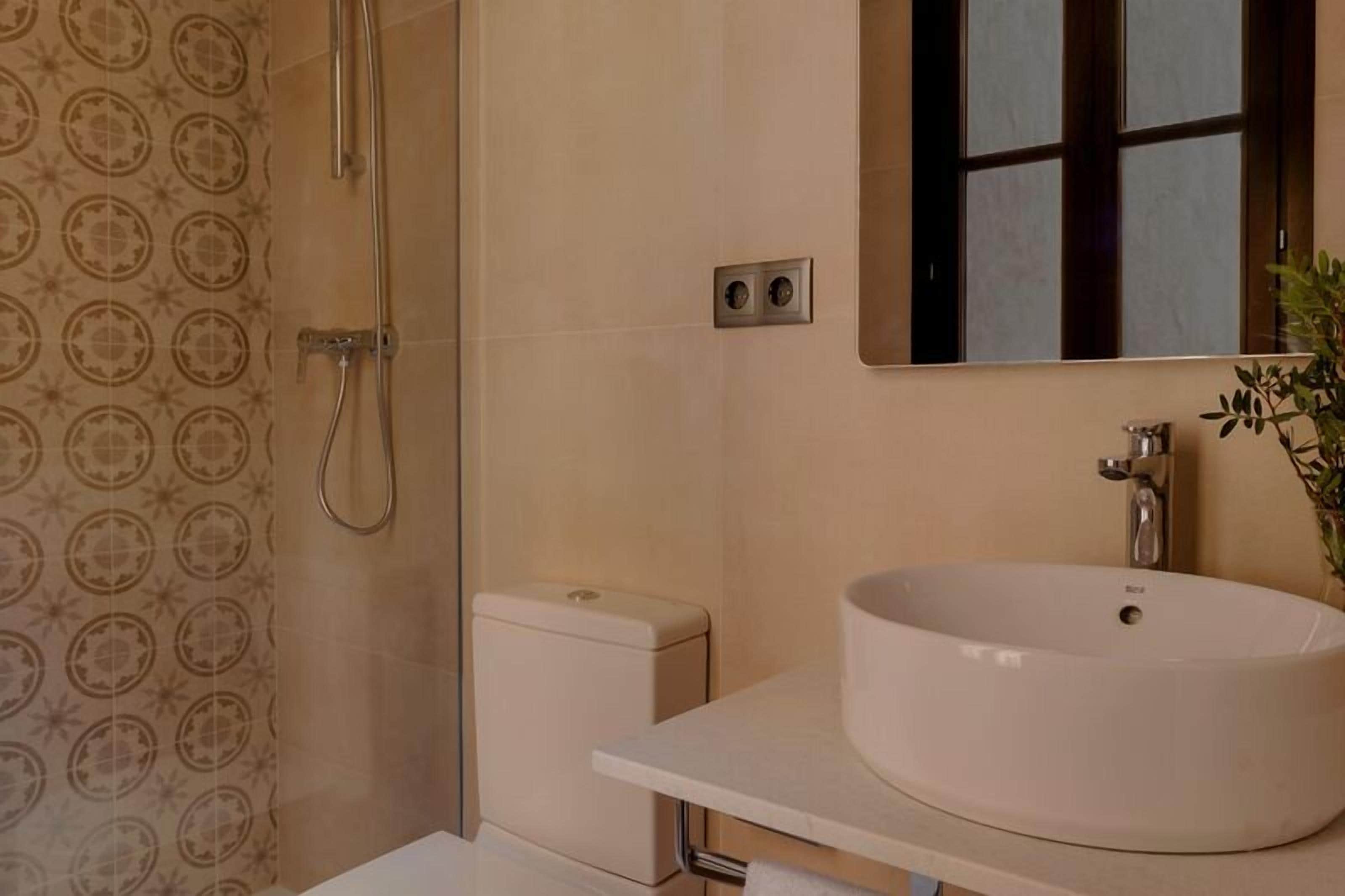 Een badkamer met toilet, wastafel, douche en spiegel.