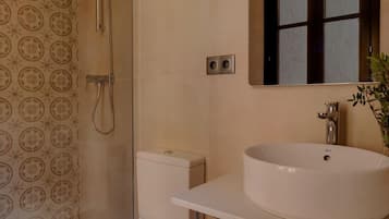 Un baño con inodoro, lavabo, ducha y espejo.