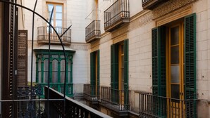 Eine enge Stadtstraße mit Häusern, die grüne Fensterläden und kunstvolle Balkone aufweisen.