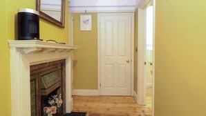 A hallway with a fireplace, a door, and a radiator. - The Anchorage (Norwich)