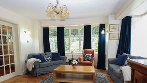 A living room with a sofa, armchair, coffee table, and a chandelier. - The Anchorage (Norwich)
