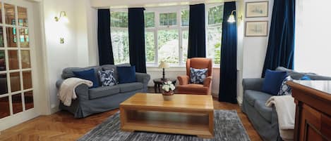 A living room with a sofa, armchair, coffee table, and a chandelier.
