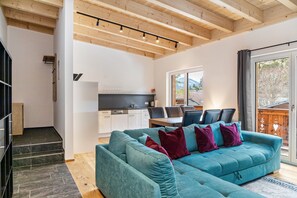 A modern living room with a teal sofa, a staircase, and a kitchen area. - Apartment 'Lorenz' with Mountain View, Balcony and Wi-Fi (Scharnitz)