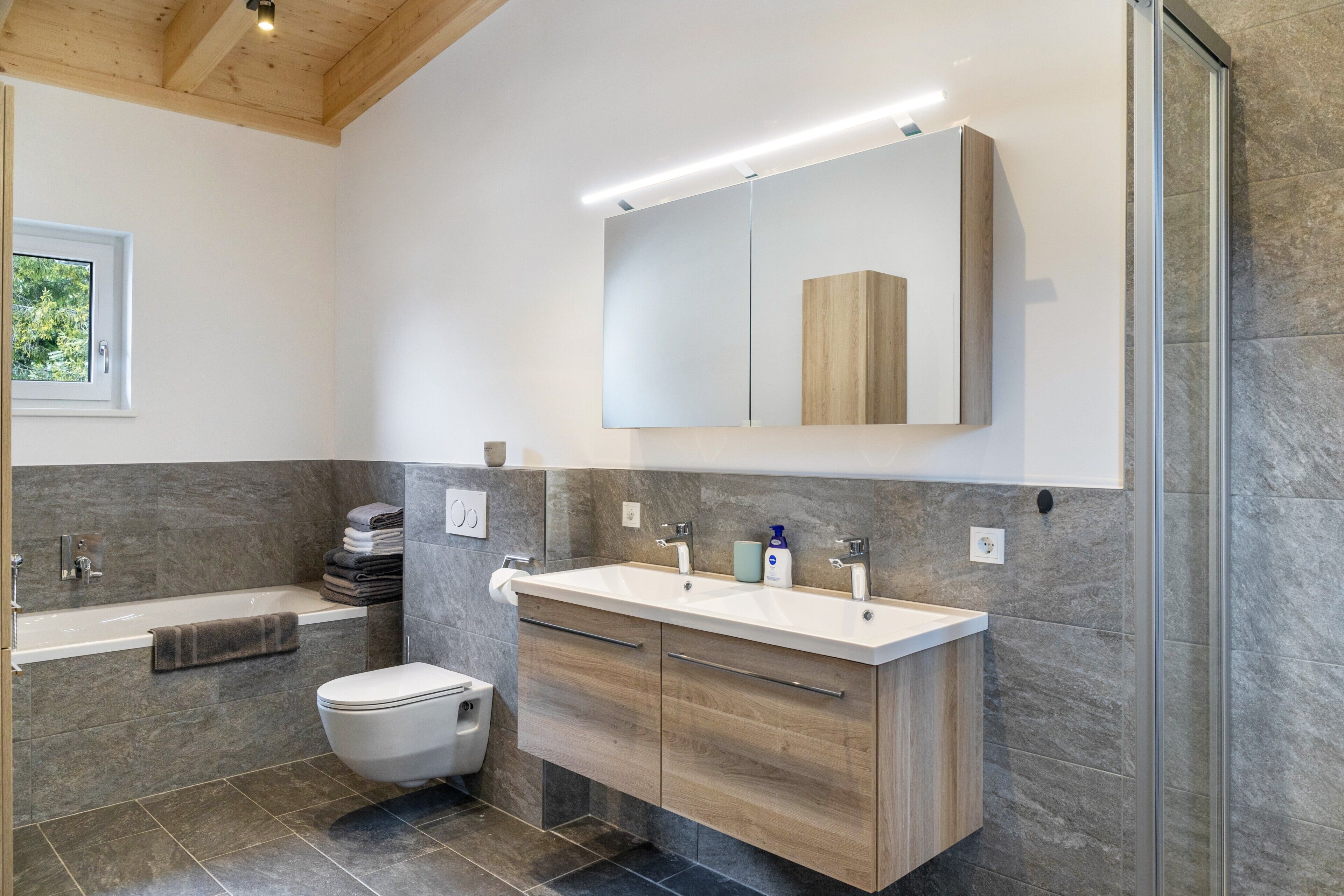 Une salle de bain moderne équipée d’une baignoire, de toilettes, d’un lavabo et d’un miroir.