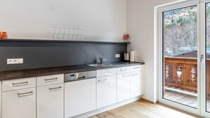 A modern kitchen with a dark countertop, white cabinets, and a built-in dishwasher.