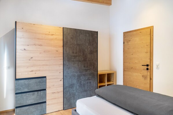 A bedroom with a bed, wooden wardrobe, and a door. - Apartment 'Lorenz' with Mountain View, Balcony and Wi-Fi (Scharnitz)