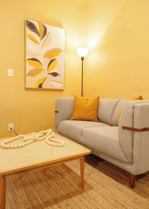 A living room with a sofa, a coffee table, a lamp, and a wall art piece. - TOP Campeche Trendy 1BR Apartment (Mexico City)