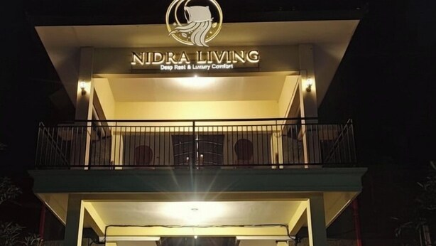Un edificio de dos pisos con un letrero que dice "NIDRA LIVING" y un logotipo encima.