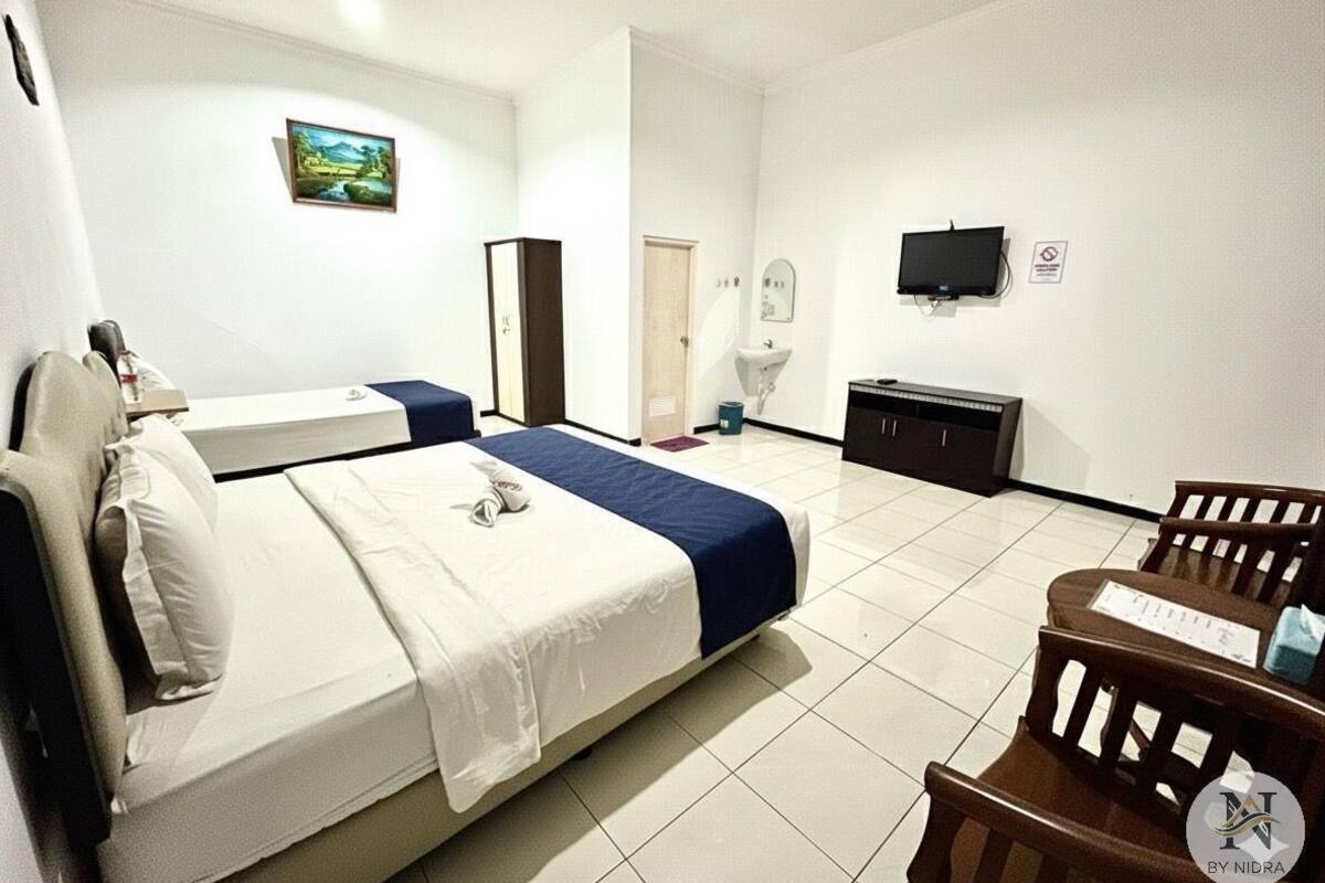 Une chambre d’hôtel avec un lit, un bureau, une chaise, une télévision, un miroir et une porte.