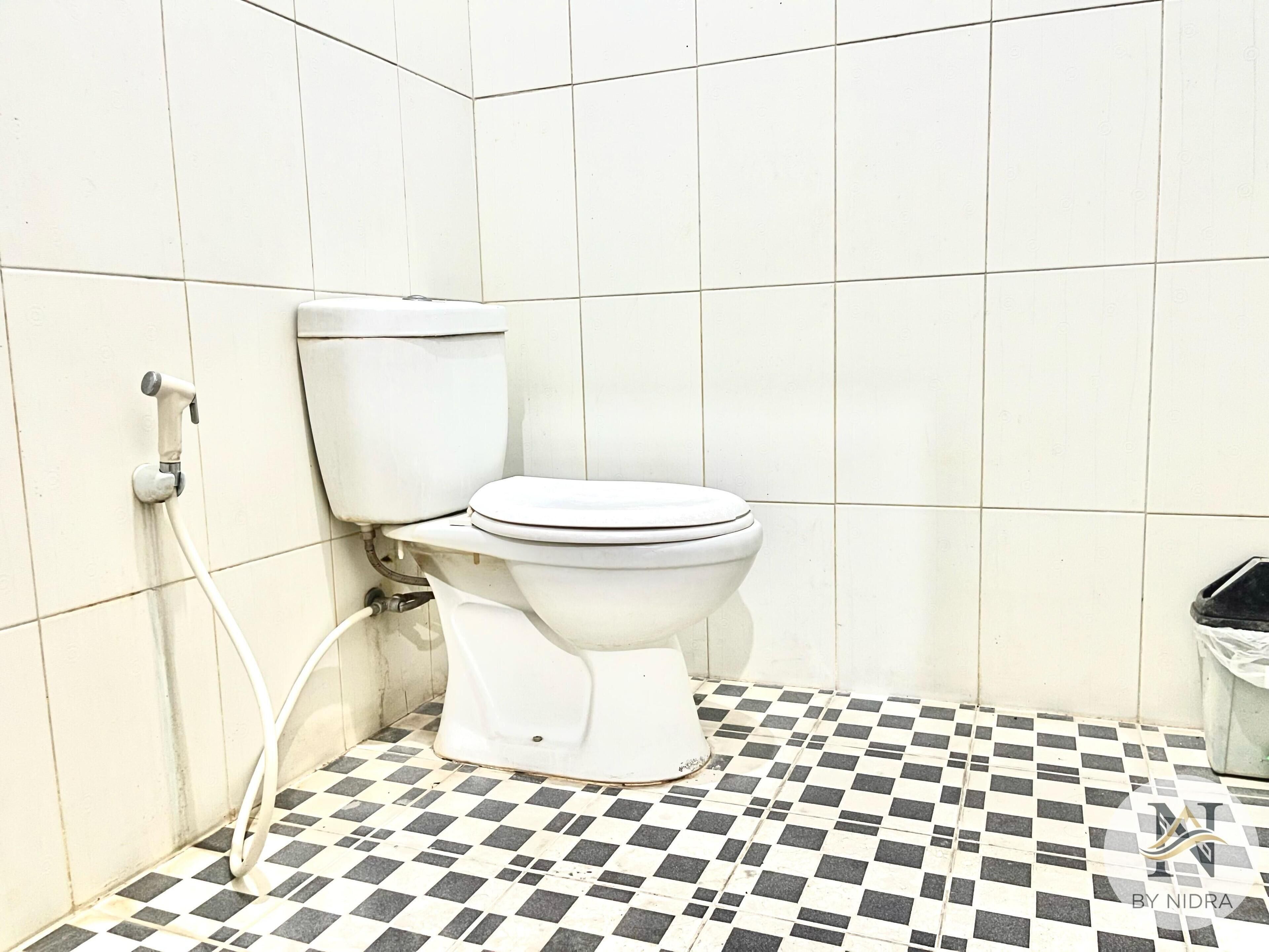 A white toilet with a tank, a bidet attachment, and a checkered floor.