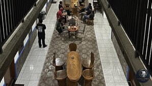 Un vestíbulo de hotel espacioso con una zona de estar central, un techo alto con tragaluces y múltiples pantallas de televisión en las paredes.