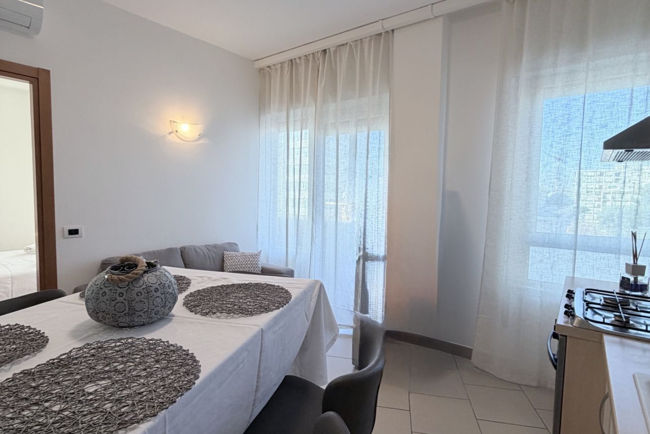 A modern dining area with a table set for four, a sofa, and a kitchen area with a gas stove.