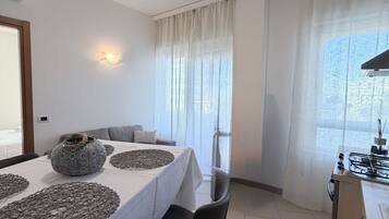 A modern dining area with a table set for four, a sofa, and a kitchen area with a gas stove.