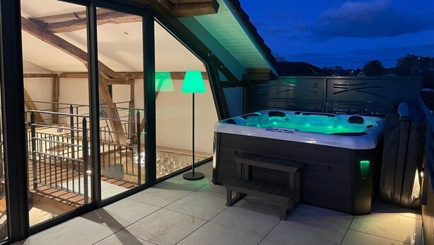 A hot tub with green lighting, a glass door leading to a balcony, and a staircase inside.