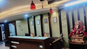 A reception desk with a wooden counter and a statue of a deity. - Hotel New Simran Palace (Hyderabad)