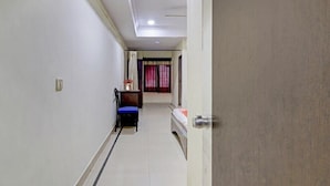 A narrow hallway with a bed, a chair, and a small table with a vase. - Hotel New Simran Palace (Hyderabad)