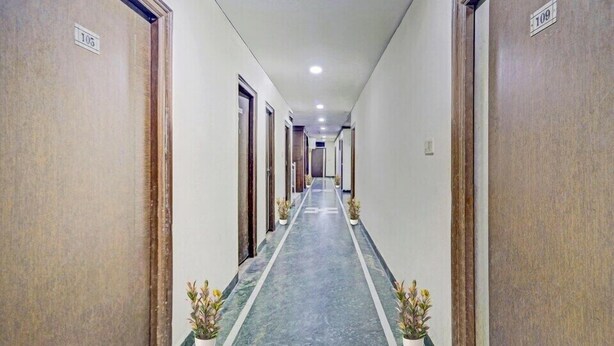 A long, narrow hallway with doors on both sides, each marked with a number. - Hotel New Simran Palace (Hyderabad)