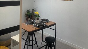 A dining area with a wooden table, black stools, and a clock on the wall. - Bagnol Cosy - Cosy apartment for 3 people, 30 min from Avignon (Bagnols-sur-Cèze)