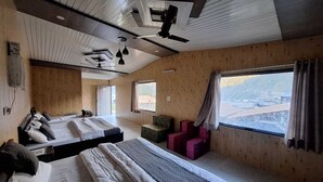 Ein Zimmer mit zwei Betten, einer kleinen Sitzecke und einem großen Fenster mit Aussicht.