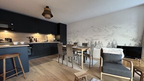 A modern kitchen with dark cabinets, a wooden island, and a dining area with a mountain mural. - Luxury apartment 2 bedrooms, Wi-Fi, pets allowed, parking (Arâches-la-Frasse)