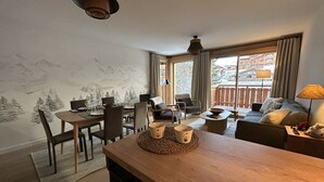 A cozy living room with a dining area, a sofa, and a balcony with a view of the mountains. - Luxury apartment 2 bedrooms, Wi-Fi, pets allowed, parking (Arâches-la-Frasse)