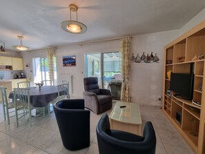 A spacious living area with a dining table, chairs, a sofa, a TV, and a bookshelf. - Holiday home for 8, near beach and sailing in Sarzeau, pets allowed (Sarzeau)
