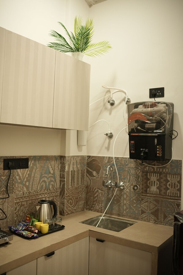 A compact kitchen with a coffee maker, a sink, and a countertop. - Hotel RJ Nesta (Jaipur)