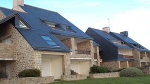 A row of modern houses with stone exteriors and dark roofs, featuring balconies and a well-maintained lawn. - Duplex for 6, direct beach access in Arzon (Arzon)