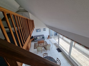 A spacious living area with a high ceiling, a wooden staircase, a sofa, a coffee table, and a view through large windows. - Duplex for 6, direct beach access in Arzon (Arzon)